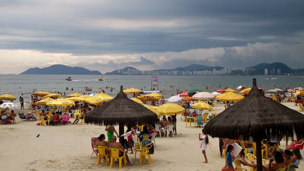 crowded beach with people and beach umbrellas surrounded by high rise buildings